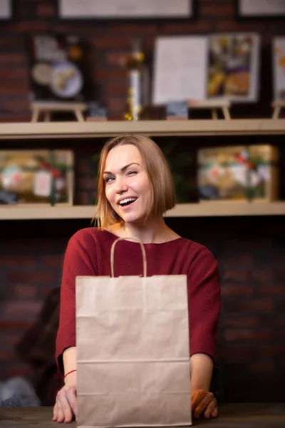 Foto des blonden Verkäufers mit Papiertüte — Stockfoto