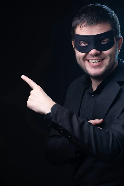 Man in black mask, jacket on empty black background. Royalty Free Stock Images