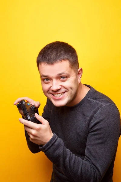 Image of man with joystick in his hands on empty orange background.