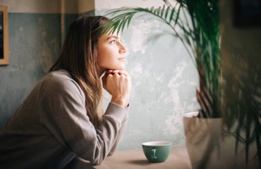 Genç kız sittings kahve masasında.