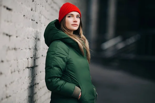 Portre sarışın yeşil ceket ve beyaz duvara yakın kırmızı şapka — Stok fotoğraf