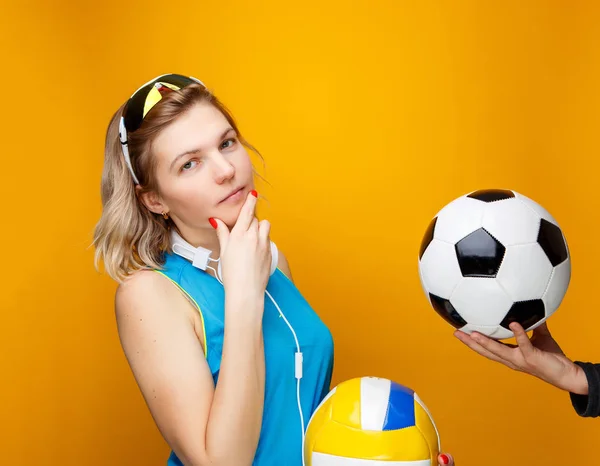 Sportswoman choisit entre le volley-ball et le ballon de football en studio  . — Photo