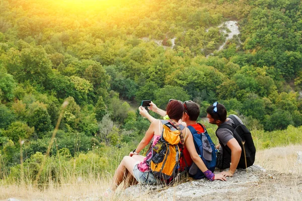 Beeld van twee mannen en vrouwen die selfie zittend op een heuvel met vegetatie — Stockfoto