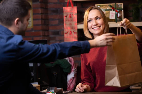 男性の買い手に紙袋を贈る笑顔の売り手女性のイメージ — ストック写真