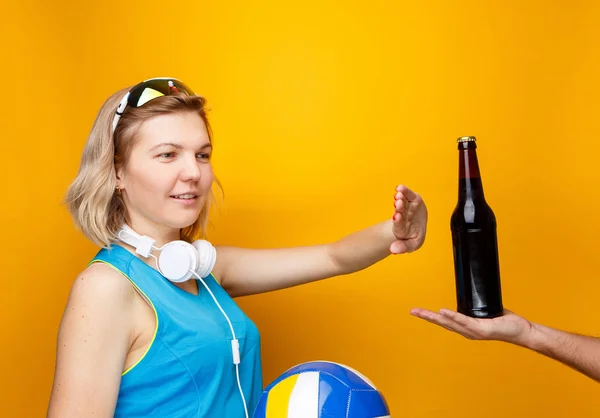 Спортсменка выбирает между волейболом и бутылкой пива в студии — стоковое фото