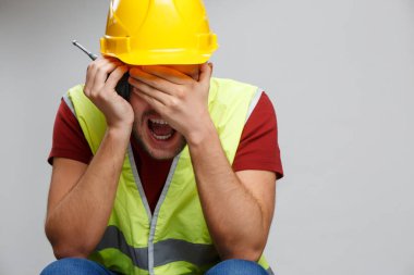 Walkie talkie ile sarı kask üzgün işçi adam fotoğrafı.
