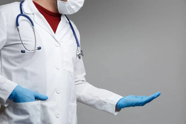Foto do médico em máscara e casaco branco com fonendoscópio com palma levantada — Fotografia de Stock