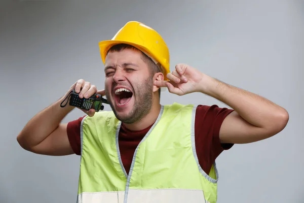 Фото кричащего строителя в желтом шлеме с рацией на пустом сером фоне . — стоковое фото