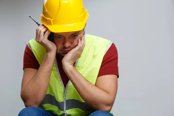 Foto de constructor infeliz macho en casco amarillo con walkie-talkie  . — Foto de Stock