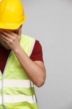 Boş gri arka planda Sarı kask mutsuz Oluşturucu adam fotoğrafı.