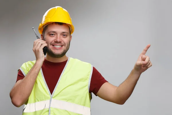 Foto van vrolijke voorman in gele helm praten over walkie-talkie wijzend zijn vinger omhoog — Stockfoto