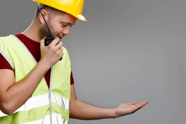 Foto de constructor en casco con walkie-talkie en la mano en chaleco amarillo con palma levantada . — Foto de Stock