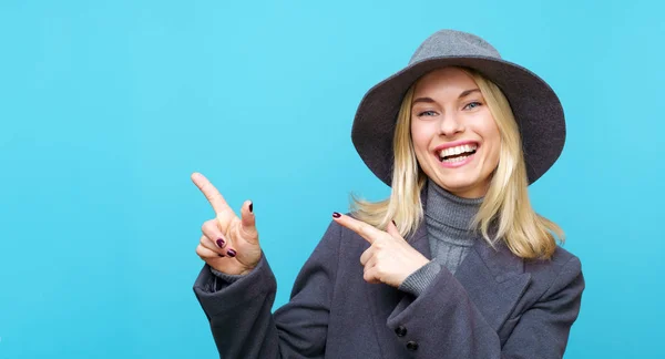 Obraz usměvavé blondýny v klobouku ukazující prst na stranu — Stock fotografie