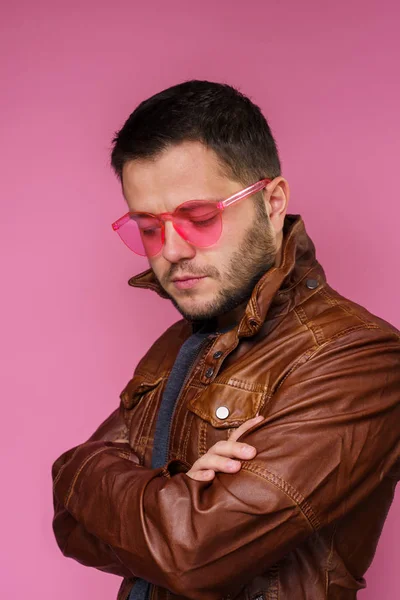 Wizerunek poważnego Brunet w różowe okulary i skórzana kurtka z ramionami skrzyżowane — Zdjęcie stockowe