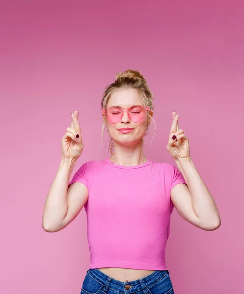 Фото улыбающейся блондинки в розовых очках, указывающей пальцем вверх — стоковое фото