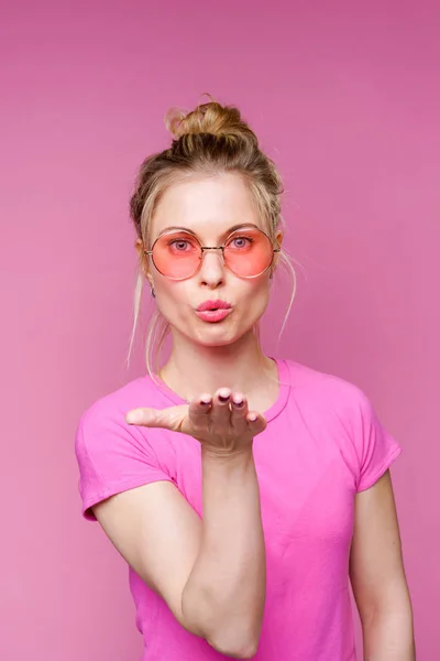 Фото блондинки в розовой футболке, дующей в поцелуй — стоковое фото