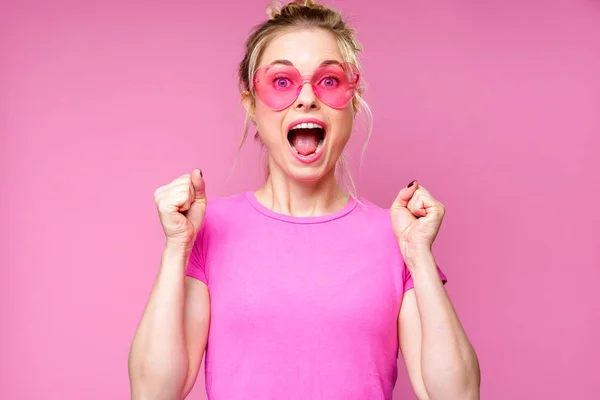 Изображение веселой блондинки в розовой футболке с поднятыми руками — стоковое фото