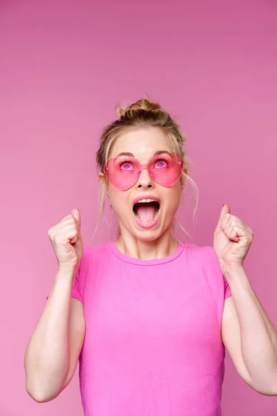 Портрет веселой блондинки в розовой футболке с поднятыми руками — стоковое фото