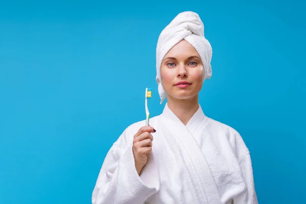 Foto van de vrouw in witte vacht en handdoek op haar hoofd met tandenborstel in haar hand — Stockfoto