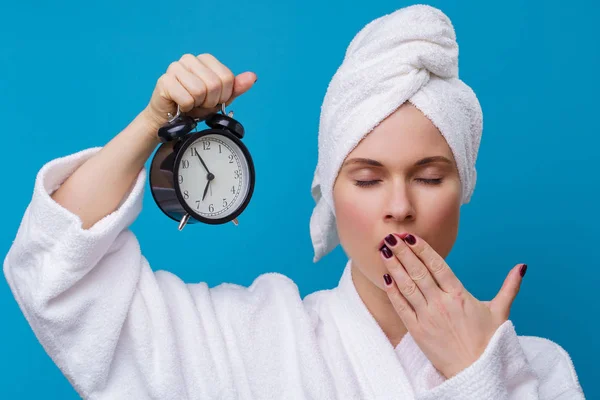 Photo of yawning woman with alarm clock