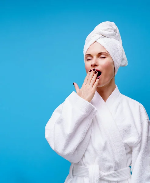 Imagen de una mujer bostezando con abrigo blanco y toalla en la cabeza — Foto de Stock