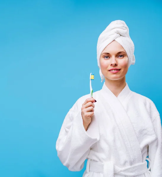 Bild einer Frau in weißem Mantel und Handtuch auf dem Kopf mit Zahnbürste in der Hand — Stockfoto