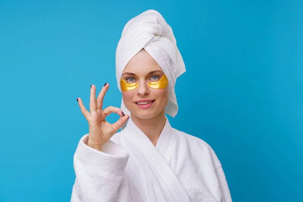 Foto av kvinna med gel kuddar under ögonen och handduk på huvudet — Stockfoto