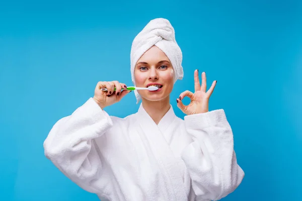 Immagine di donna in cappotto bianco e asciugamano sulla testa lavarsi i denti — Foto Stock