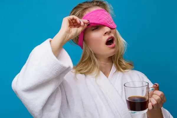 Foto de mujer bostezando con parche de ojo rosa y taza de café — Foto de Stock