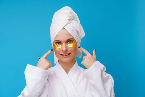 Изображение женщины с гелевыми прокладками под глазами и полотенцем на голове — стоковое фото