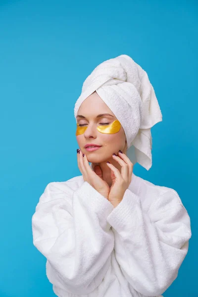 Foto van de jonge vrouw met gesloten ogen met gelpads onder de ogen en handdoek op het hoofd — Stockfoto