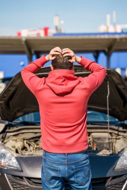 Gündüz kırık arabanın açık kaputunun yanındaki erkeğin sırtındaki görüntü