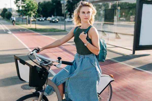 Fotó a szőke nő ül a kerékpáros közelében buszmegálló — Stock Fotó