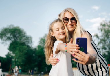 Mutlu anne ve kızının yaz günü sokakta selfie çekerken görüntüsü