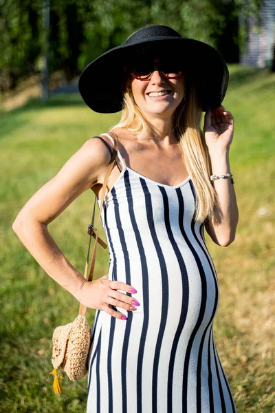 Foto van zwangere vrouw in lange jurk staande op straat — Stockfoto