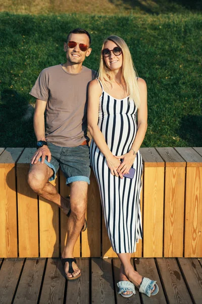 Foto van zwangere vrouw en man staande in de buurt van houten hek op zomerdag — Stockfoto