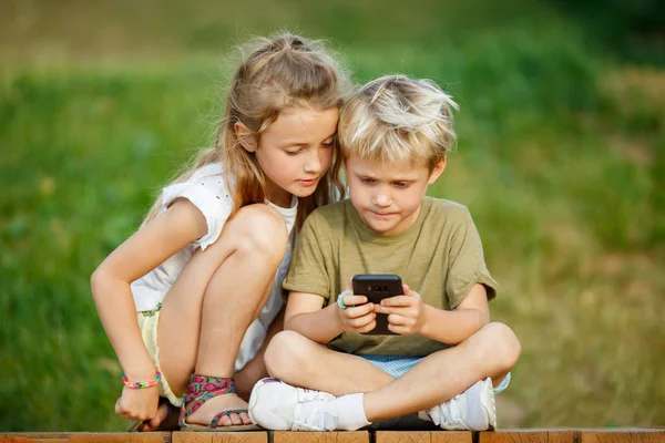 Açık havada ahşap çit üzerinde oturan telefonlar elleri ile erkek ve kız Görüntü