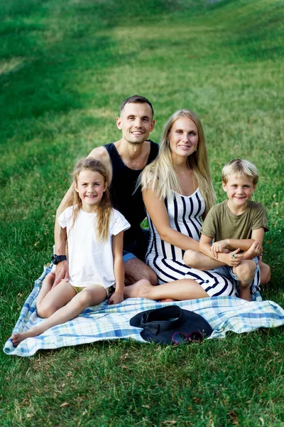 Kép a szülők gyerekekkel ült kockás piknik a nyári napon — Stock Fotó