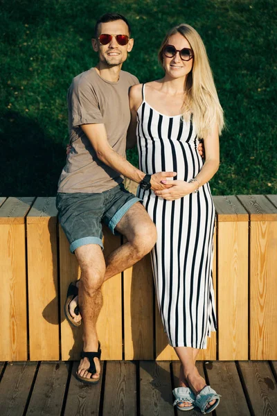 Image of pregnant woman and man standing near wooden fence on summer day — Stock Photo, Image