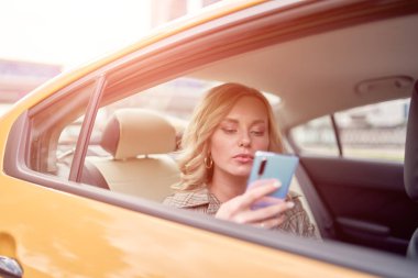 Öğleden sonra sarı taksi arka koltukta oturan elinde telefon ile sarışın fotoğraf