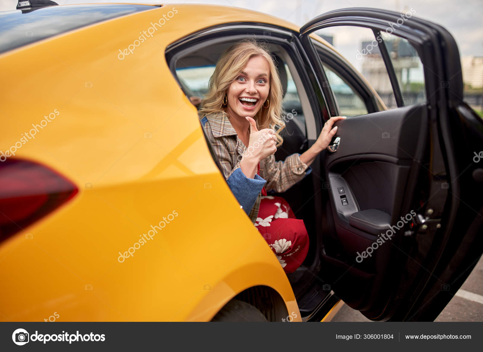 Photo of enthusiastic blonde sitting in back seat of yellow taxi