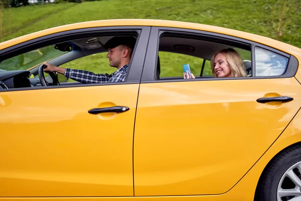 Изображение водителя желтого такси, сидящего за рулем, и блондинки, сидящей на заднем сидении — стоковое фото