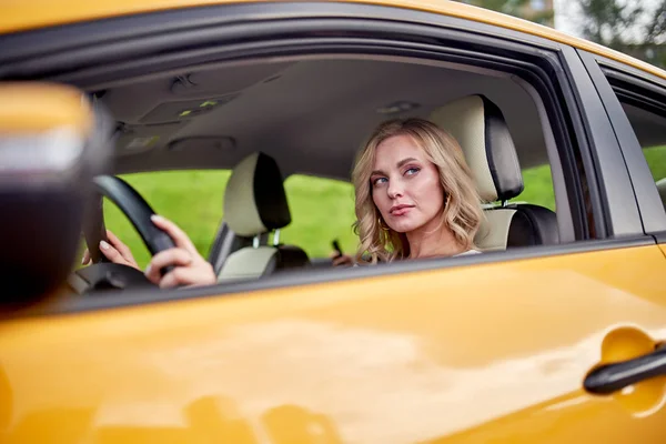 곱슬 금발의 사진 운전 노란색 자동차 — 스톡 사진