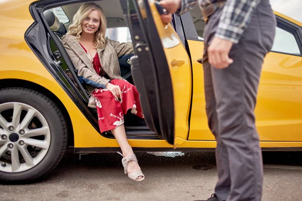 Immagine di donna bionda in abito rosso lungo seduta in taxi e uomini che aprono la porta — Foto Stock