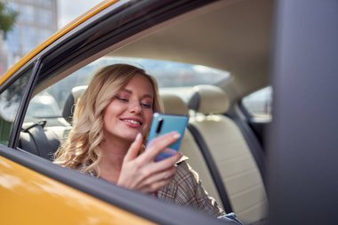 Sarı taksi arka koltukta oturan elinde telefon ile mutlu sarışın fotoğrafı