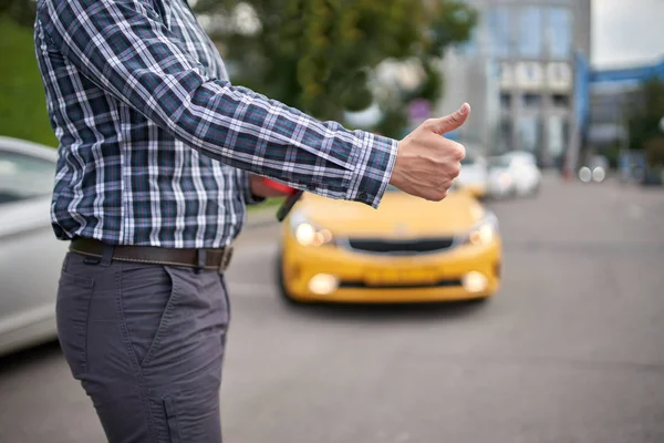 Картина людини з простягнутою рукою зупиняє таксі вдень на розмитому фоні . — стокове фото