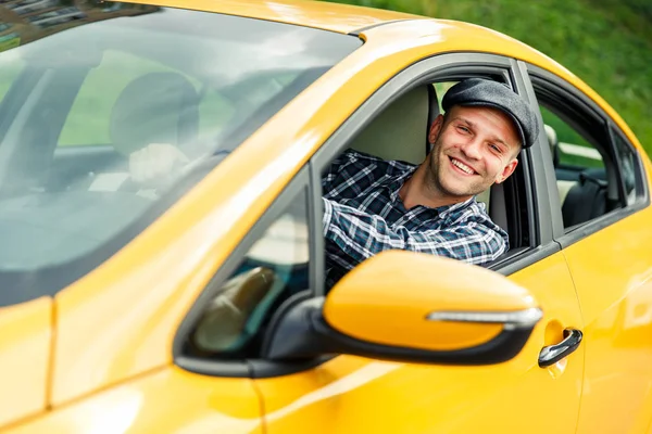 Image of happy driver in plaid shirt sitting in yellow taxi on summer