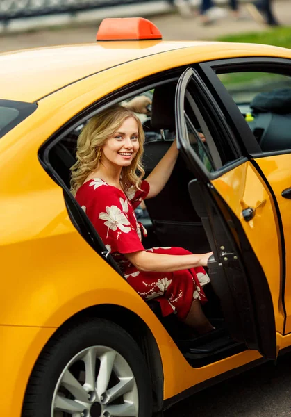 Photo of blonde in red dress sitting in taxi on summer. — Stock Photo, Image
