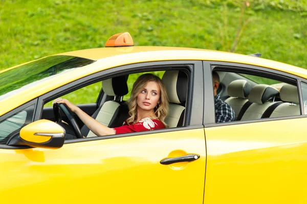 Фото блондинки-водительницы, сидящей летом в желтом такси — стоковое фото