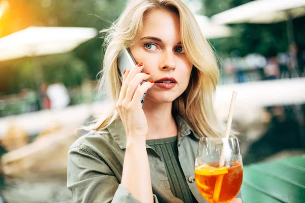 Foto de loira com coquetel nas mãos falando por telefone na rua . — Fotografia de Stock